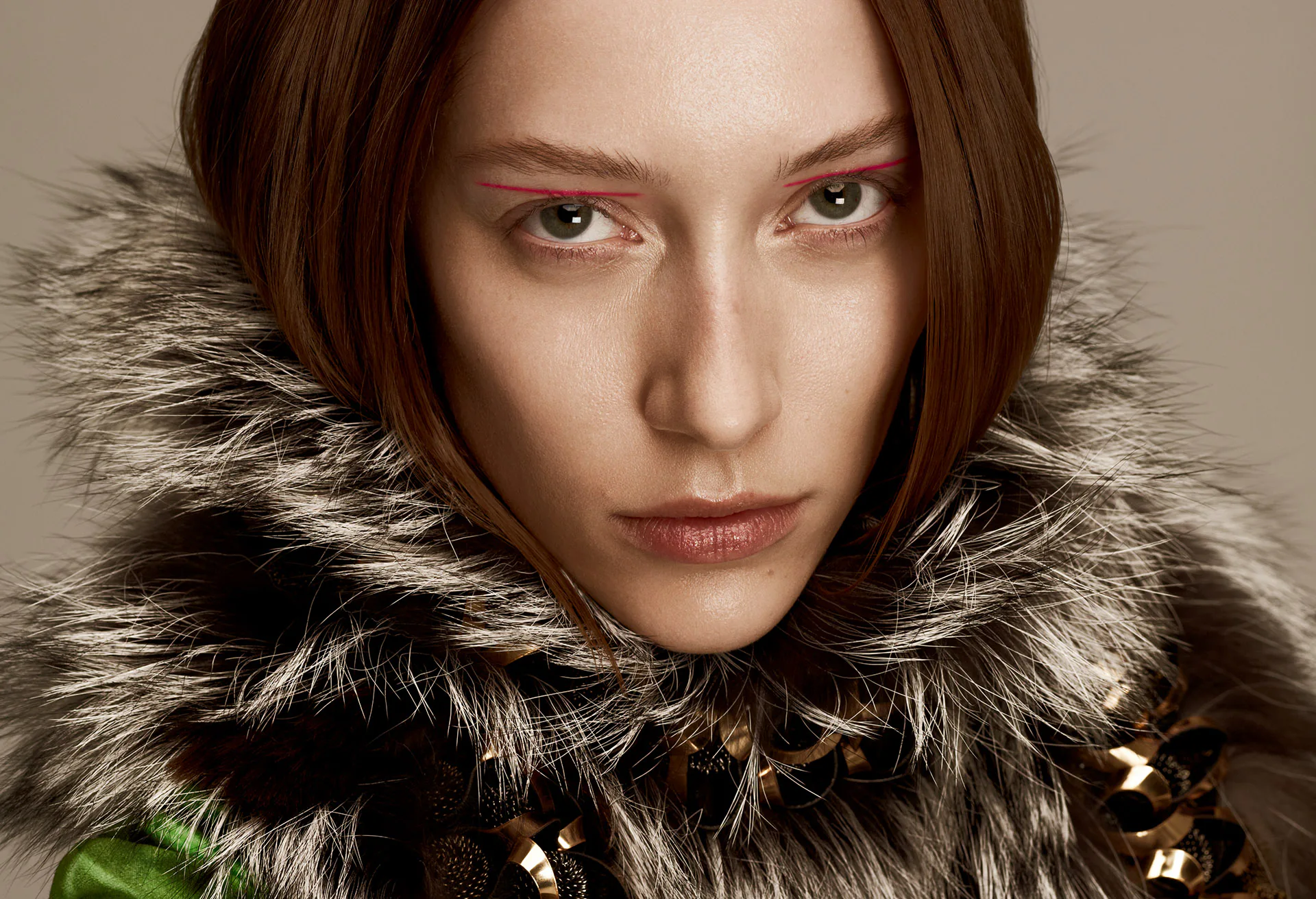 A close beauty portrait, the model in a fur collar and gold jewellery.