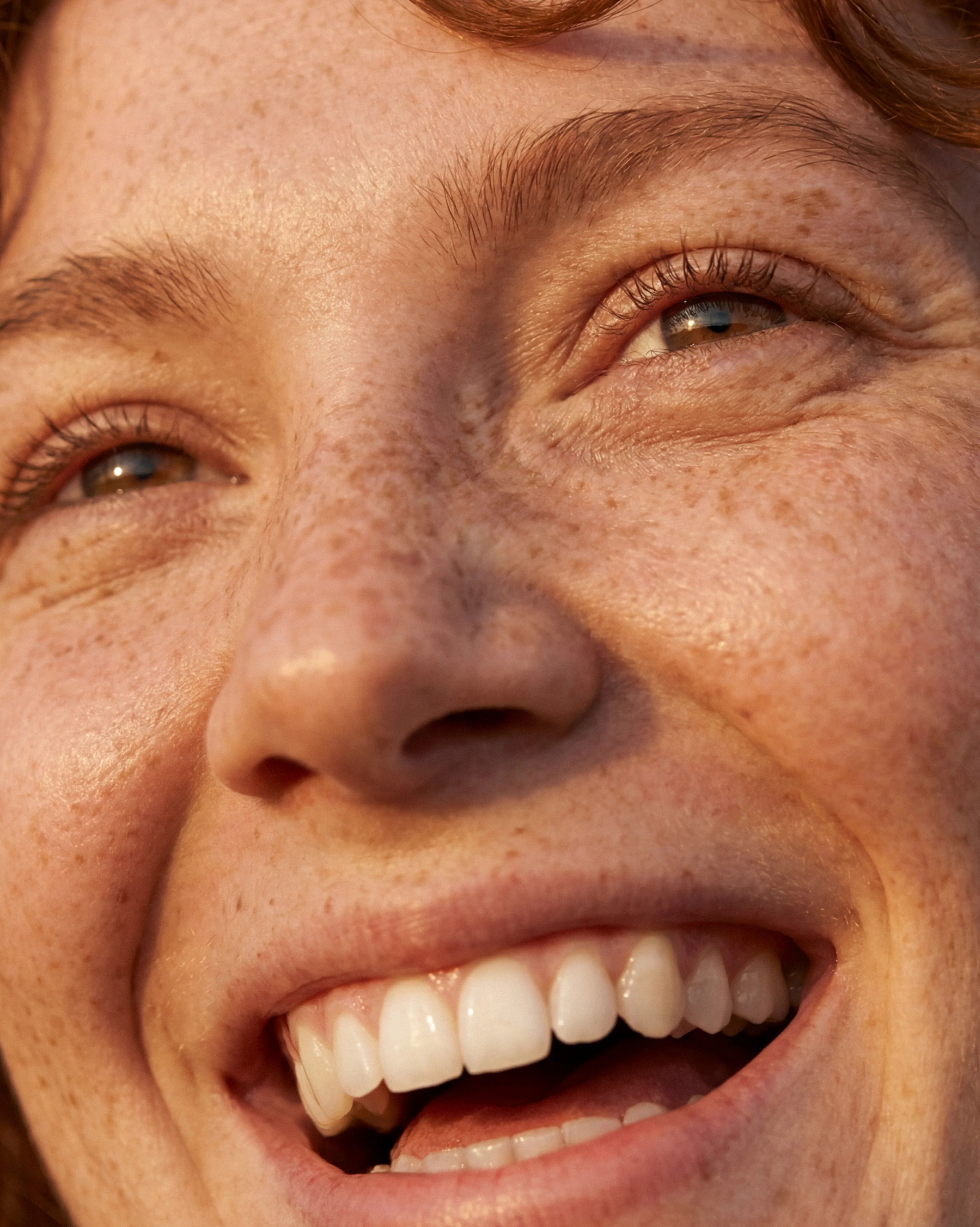 Close-up portrait of a smiling woman with freckles, from the e-LINE photography direction