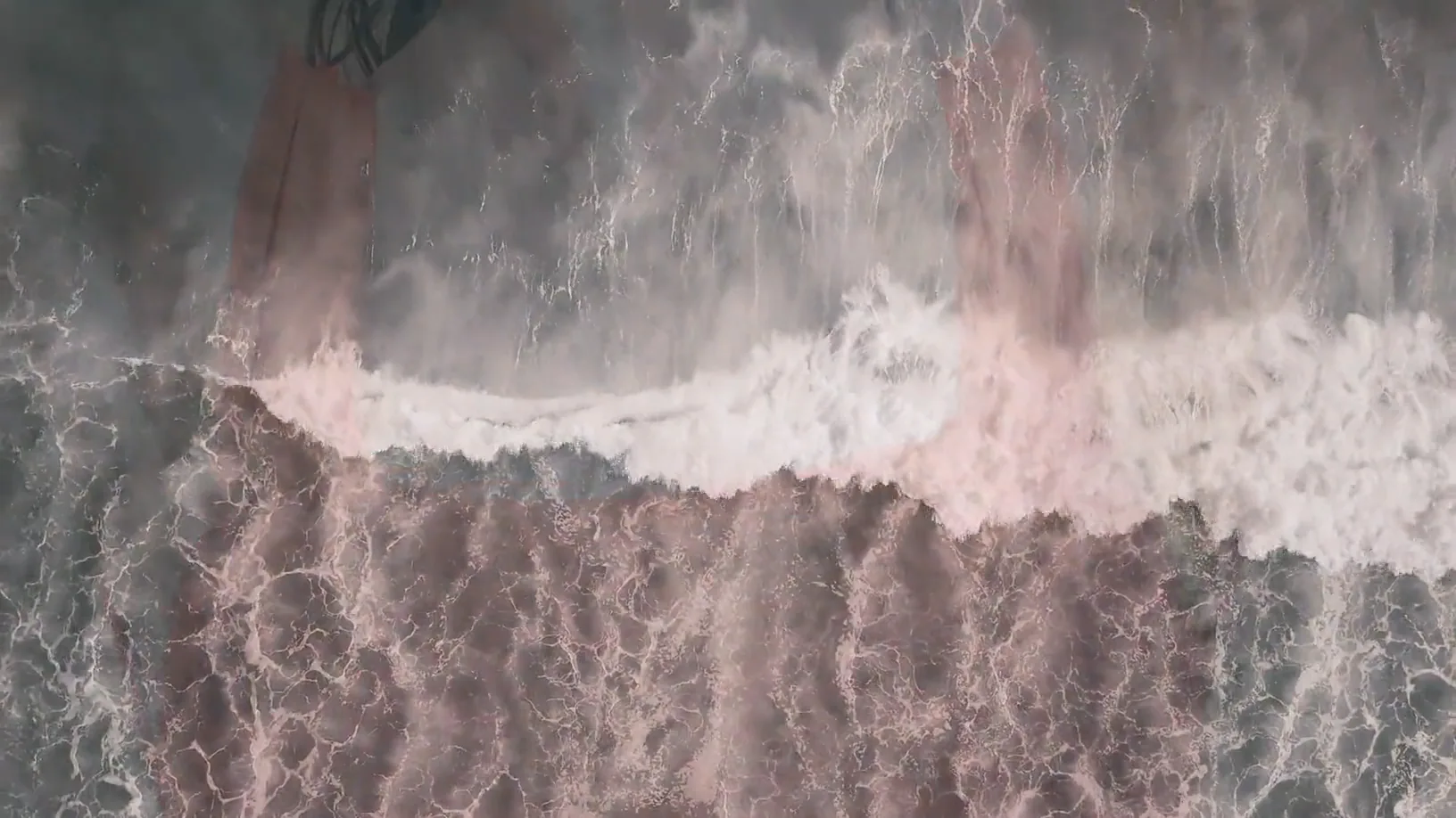 A breaking wave dissolving into close portraits and a coral swimsuit, in washed pale tones.