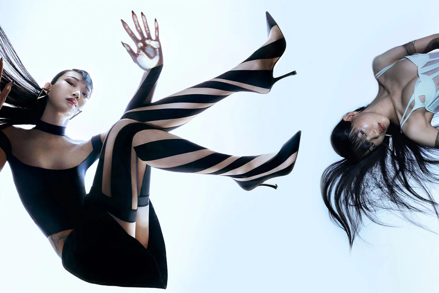 Two figures against a pale sky, striped fabric streaming between them.